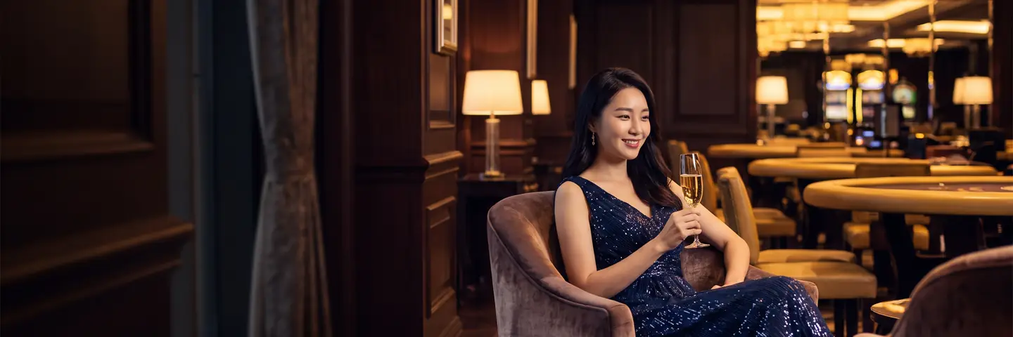 네온 라운지 배경에서 VIP 라운지 의자에 앉은 이브닝드레스 차림의 여성 – 볼트카지노 입금 플러스 무한도전